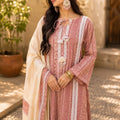 Woman wearing a patterned dress with a beige shawl outdoors.