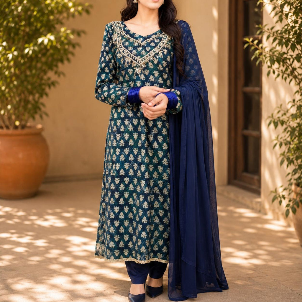 Woman wearing a green and blue traditional outfit with a blue dupatta in an outdoor setting.