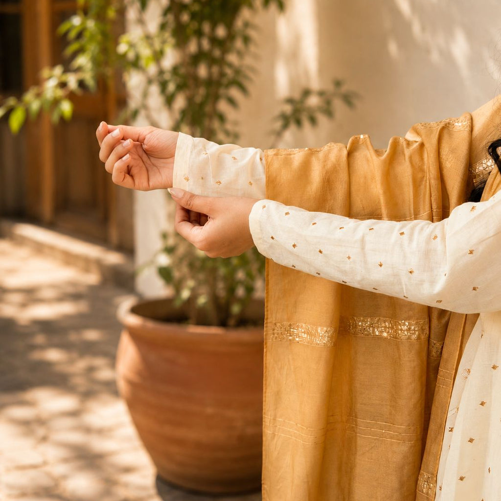 Woman wearing a mustard yellow and white traditional outfit with long sleeves