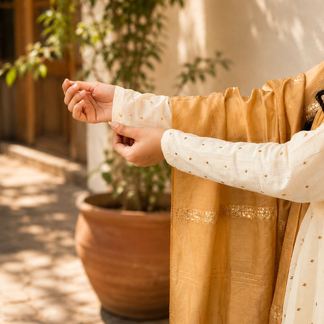 Woman wearing a mustard yellow and white traditional outfit with long sleeves